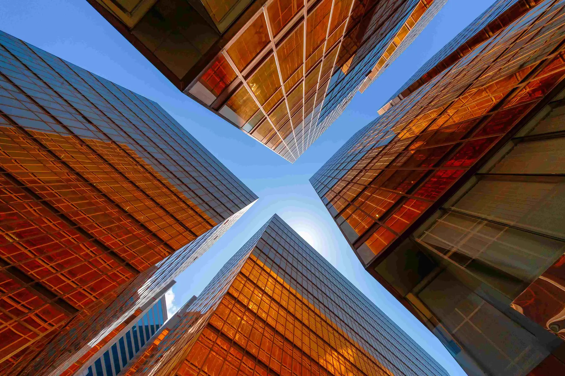 Office towers seen from below, their glass facades converging against the sky